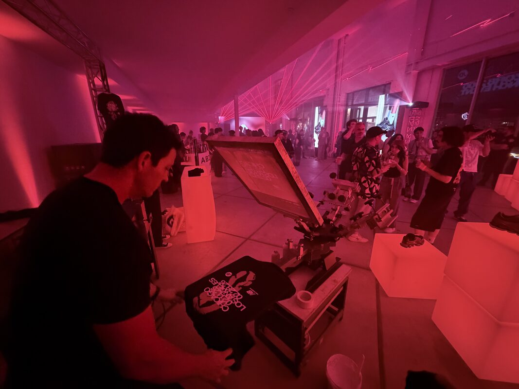 Operator printing shirts live at a nighttime brand party lit in red