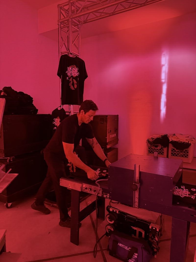 Backstage garment prep with a conveyor dryer and stacked apparel under red lights