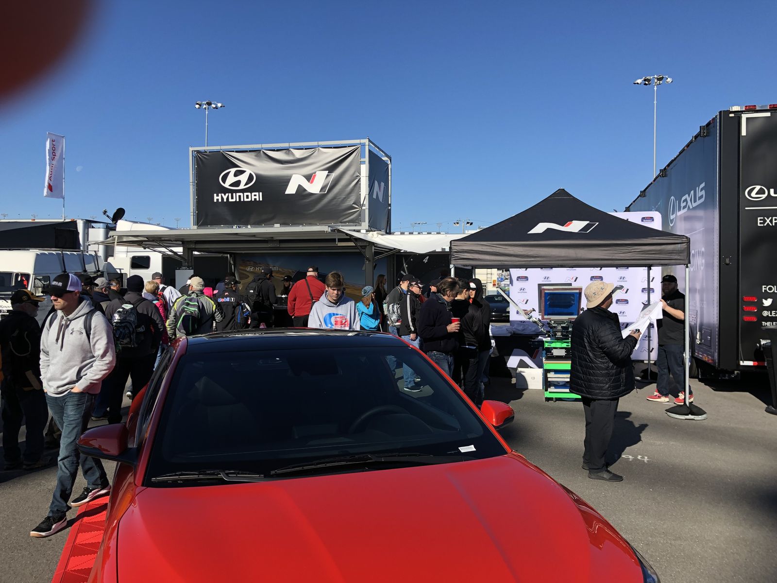 Crowd gathered around a brand activation tent with a live printing setup at a raceway