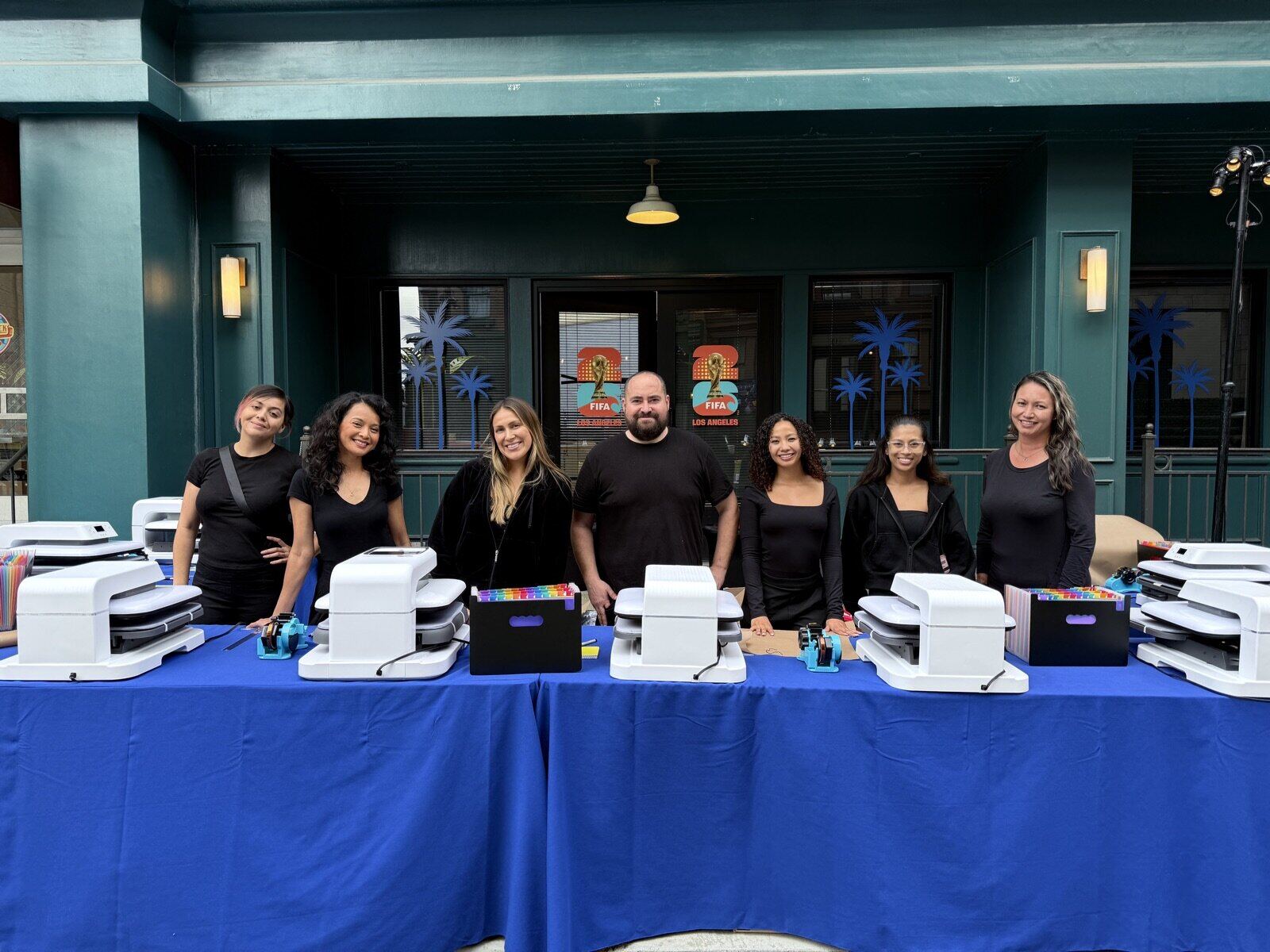 Merch Troop mobile printing crew standing behind a row of heat presses at an outdoor event